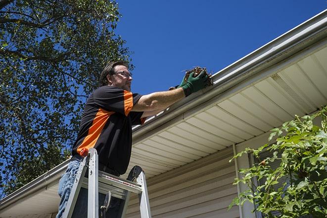 a gutter repair technician using a ladder and tools in Aurora, IL